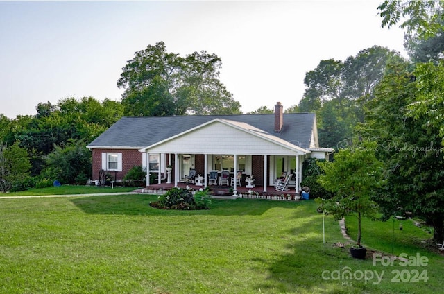 rear view of property featuring brick siding, a lawn, a porch, and a chimney