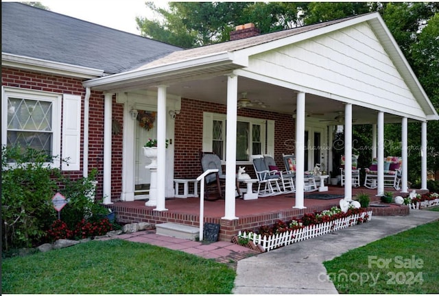 entrance to property with brick siding, covered porch, a chimney, and ceiling fan