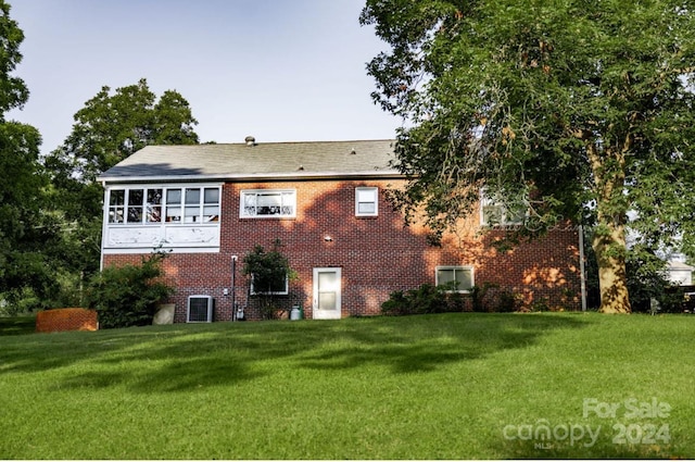 back of house with brick siding and a lawn