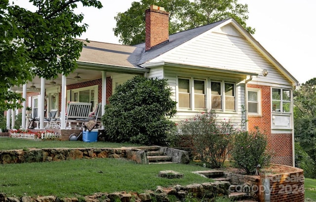 view of front of home featuring brick siding, covered porch, a chimney, and a front lawn