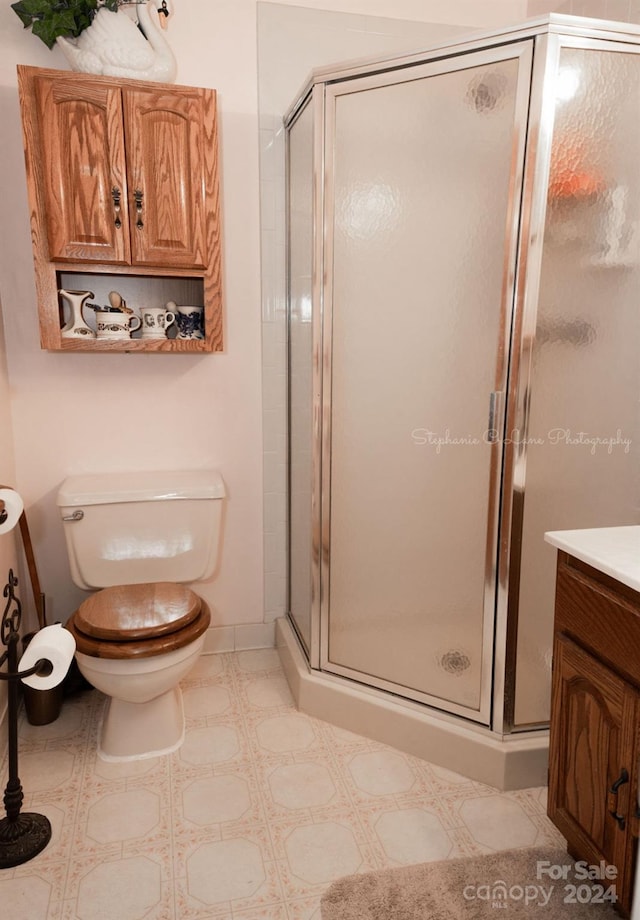 bathroom featuring baseboards, vanity, toilet, and a shower stall