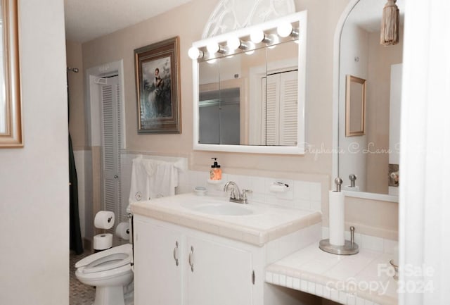 bathroom with a closet, toilet, and vanity