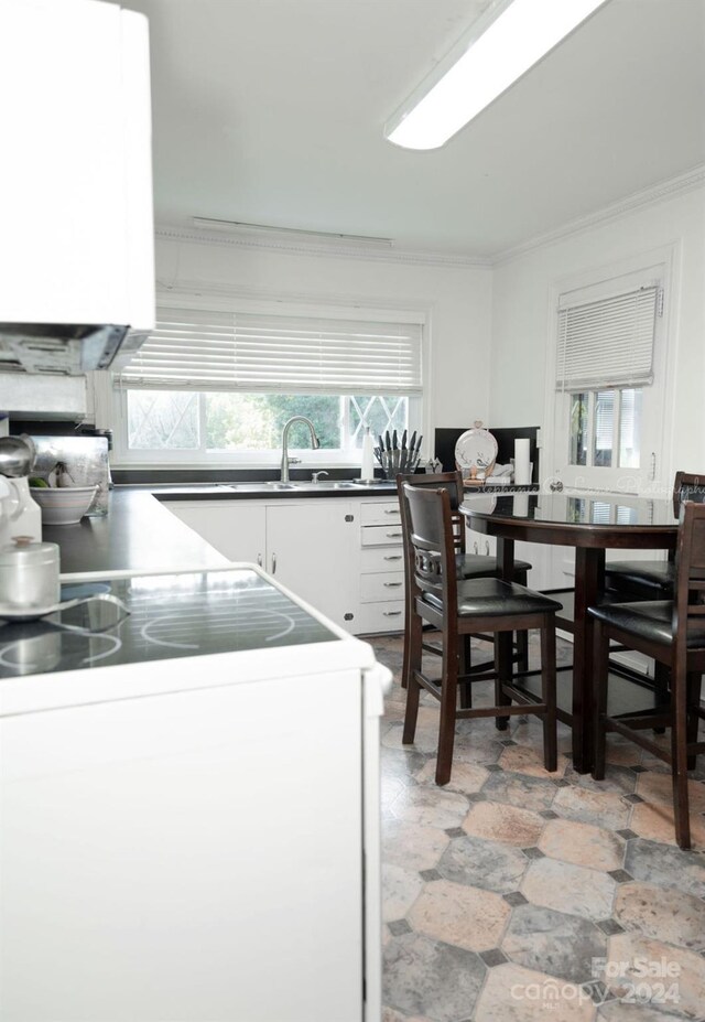 kitchen with crown molding, white cabinetry, and stove