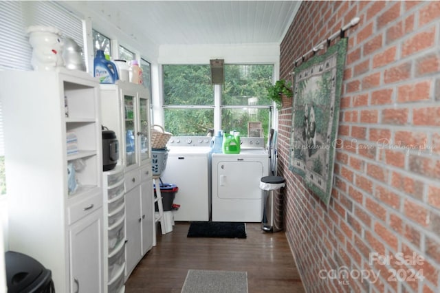 laundry room with dark wood-type flooring, brick wall, and washing machine and dryer