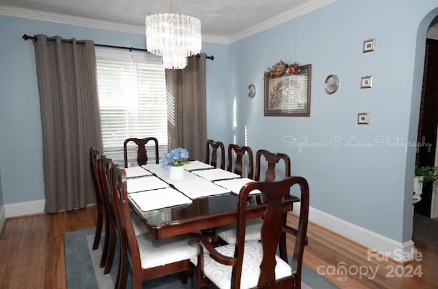 dining room with wood finished floors, baseboards, arched walkways, and ornamental molding