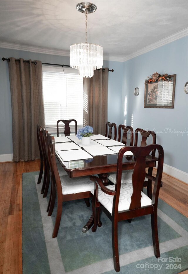 dining area with an inviting chandelier, crown molding, and dark hardwood / wood-style flooring