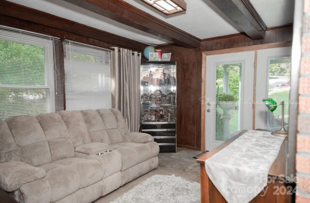 living room featuring light carpet, ornamental molding, beam ceiling, and wooden walls