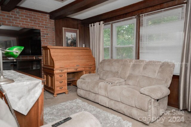 living room featuring beamed ceiling, wooden walls, and ornamental molding