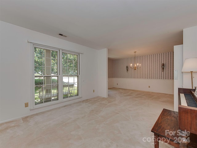 unfurnished room featuring a chandelier and light colored carpet