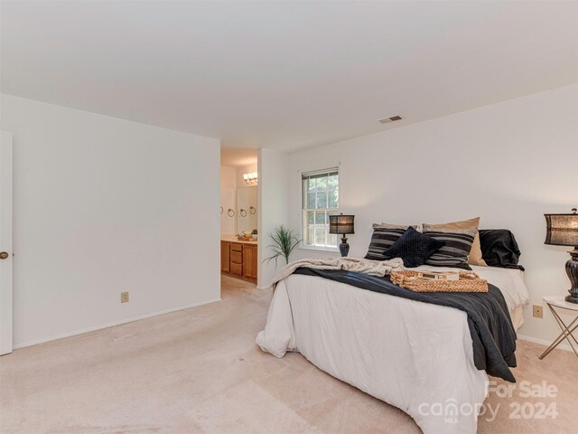 bedroom featuring ensuite bath and light colored carpet