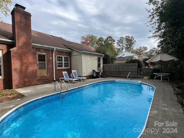 view of pool featuring a patio, a fenced in pool, fence, and a grill