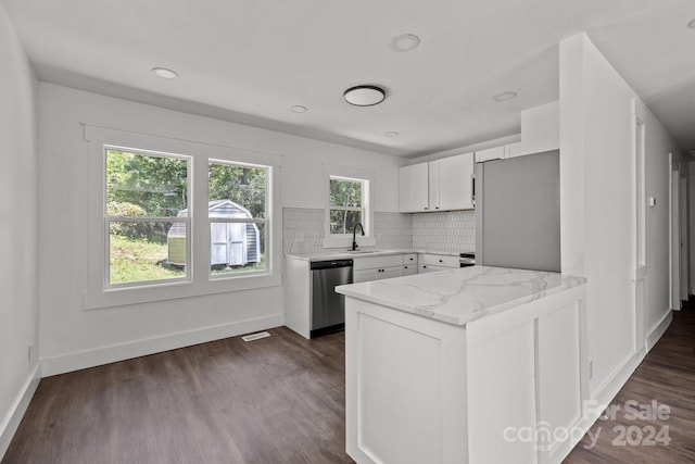 kitchen with a peninsula, white cabinets, appliances with stainless steel finishes, decorative backsplash, and dark wood-style floors