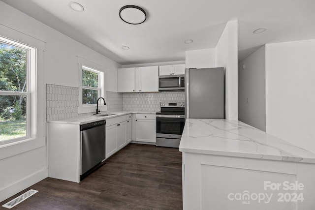 kitchen featuring dark wood-style floors, stainless steel appliances, visible vents, decorative backsplash, and a sink