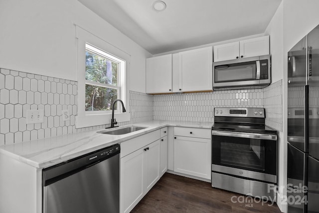 kitchen with appliances with stainless steel finishes, a sink, light stone counters, and white cabinets