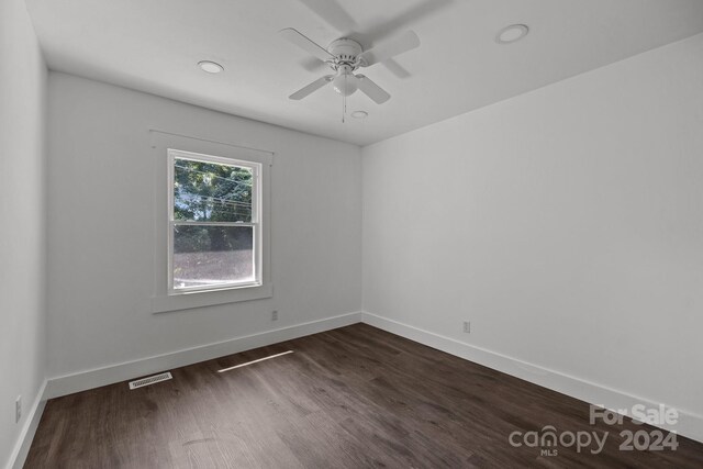 unfurnished room featuring a ceiling fan, dark wood finished floors, visible vents, and baseboards