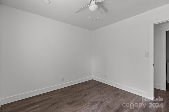 empty room with ceiling fan, dark wood finished floors, and baseboards