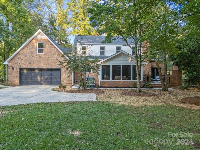 view of front property with a sunroom, a front lawn, and a garage