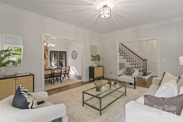 living room with hardwood / wood-style floors, an inviting chandelier, plenty of natural light, and crown molding