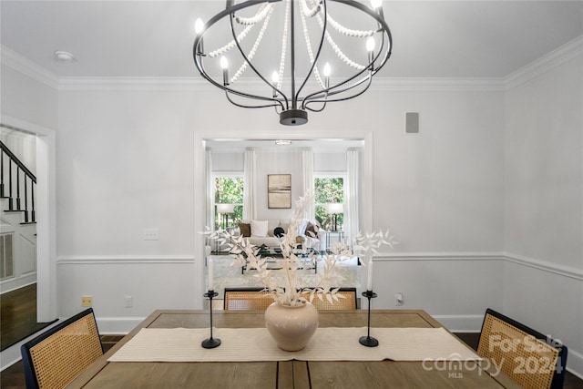 dining room with hardwood / wood-style floors, ornamental molding, and a notable chandelier