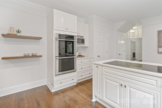 kitchen with white cabinets, appliances with stainless steel finishes, ornamental molding, and wood-type flooring