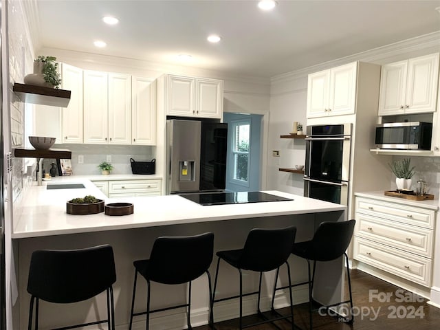 kitchen with white cabinets, appliances with stainless steel finishes, a kitchen bar, and decorative backsplash