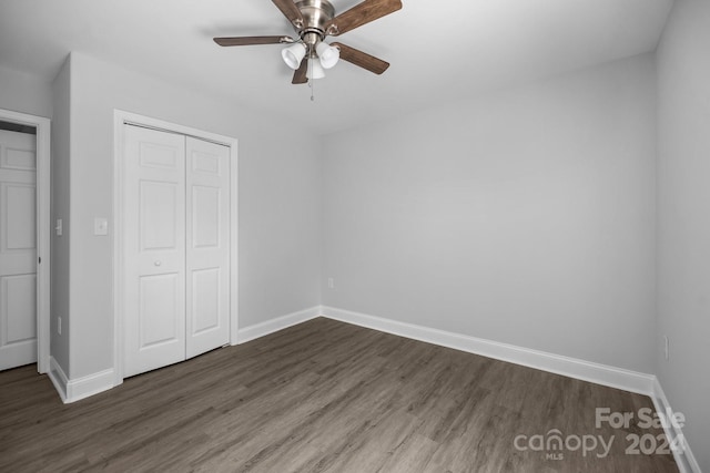 unfurnished bedroom with dark hardwood / wood-style flooring, ceiling fan, and a closet