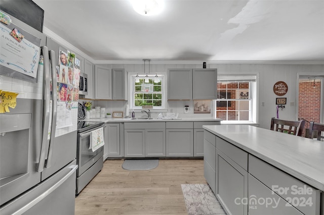 kitchen with light wood-style flooring, appliances with stainless steel finishes, a sink, and gray cabinetry