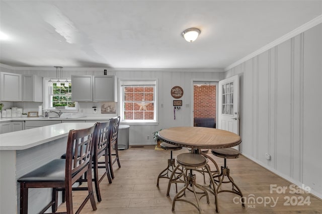 dining area with light wood-type flooring and crown molding