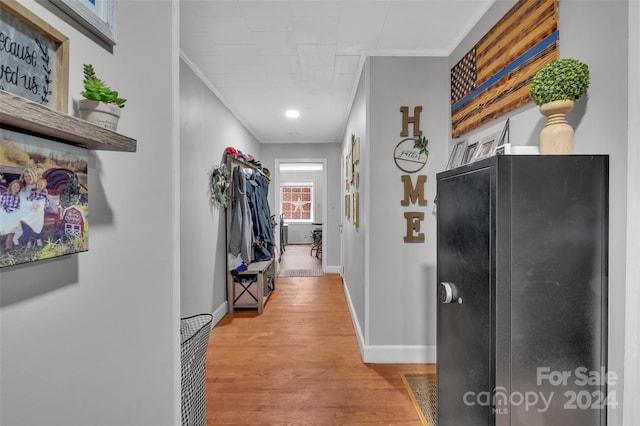 hall with ornamental molding, light wood-type flooring, and baseboards