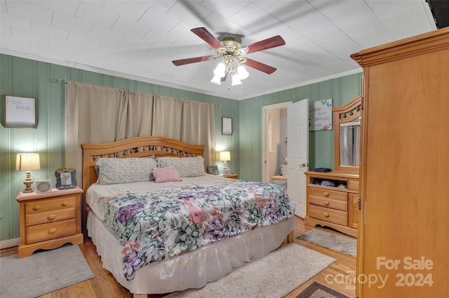 bedroom featuring ceiling fan, ensuite bathroom, wood finished floors, and crown molding