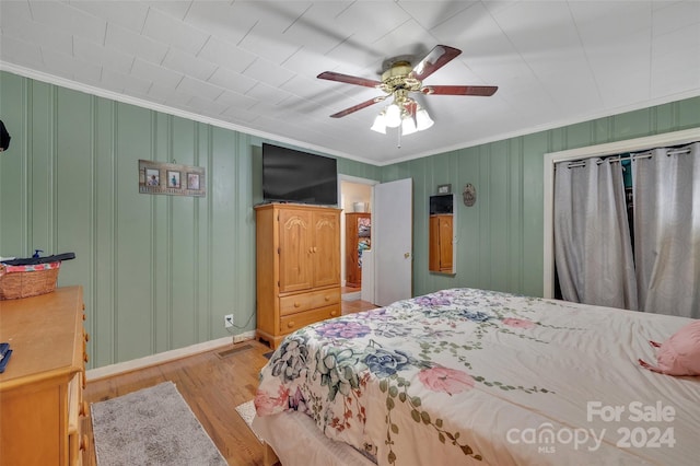 bedroom featuring ornamental molding, wood finished floors, and a ceiling fan