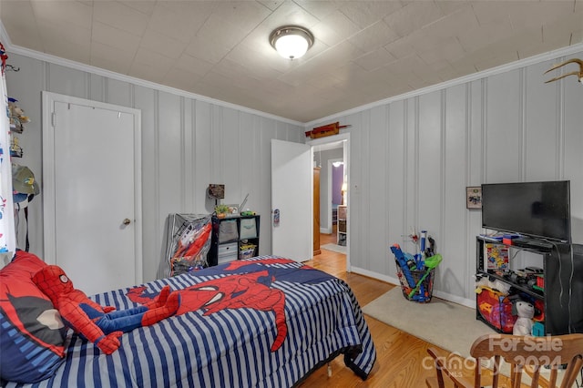 bedroom with wood finished floors and crown molding