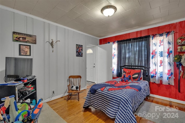 bedroom featuring multiple windows, crown molding, and wood finished floors