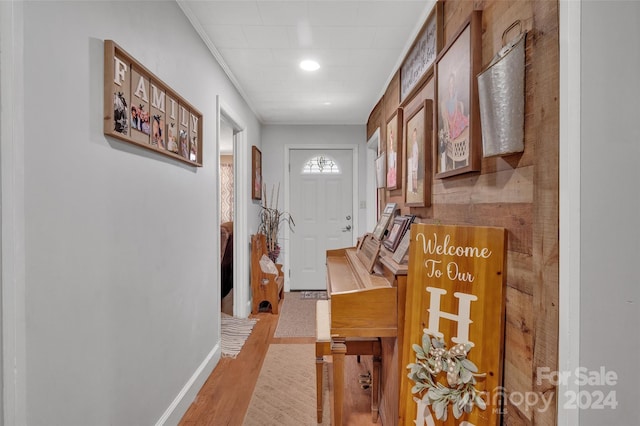 hallway featuring baseboards, wood finished floors, and ornamental molding