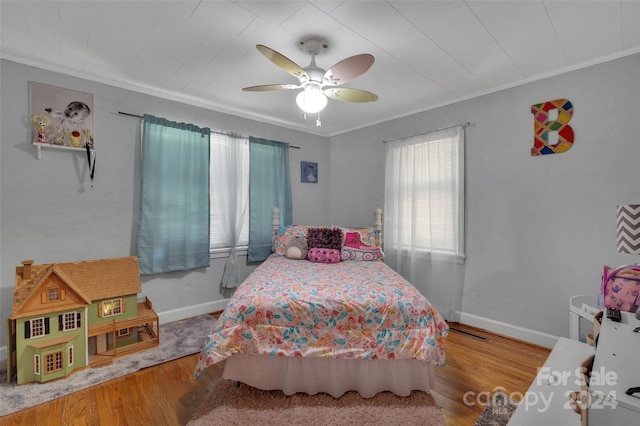 bedroom with baseboards, wood finished floors, a ceiling fan, and crown molding