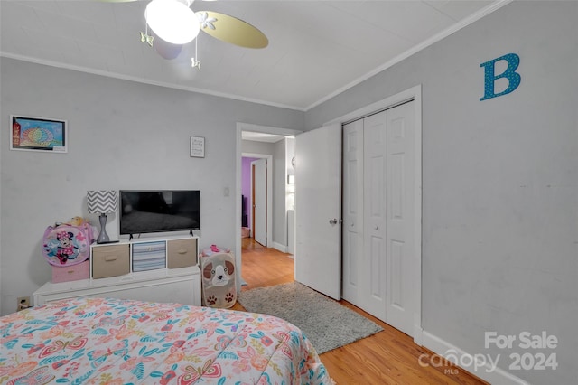 bedroom featuring baseboards, a ceiling fan, wood finished floors, crown molding, and a closet