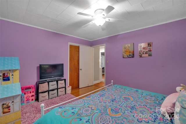 bedroom with a ceiling fan, ornamental molding, and wood finished floors