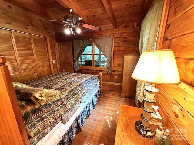 bedroom featuring wooden ceiling, a closet, beam ceiling, hardwood / wood-style flooring, and wooden walls