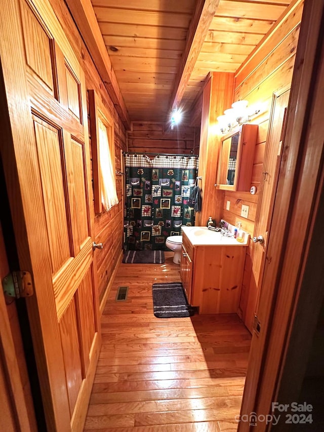 bathroom featuring toilet, wooden walls, hardwood / wood-style flooring, and vanity