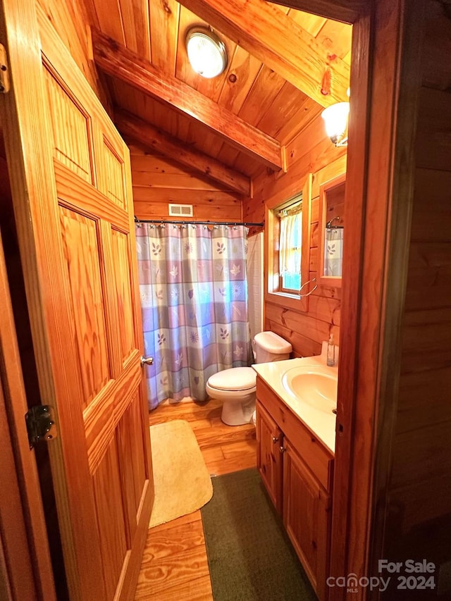 bathroom with wooden walls, hardwood / wood-style floors, toilet, vanity, and vaulted ceiling with beams