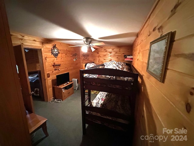 bedroom with ceiling fan, wooden walls, and carpet flooring