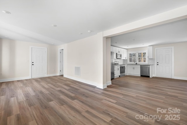 unfurnished living room with wood-type flooring and sink