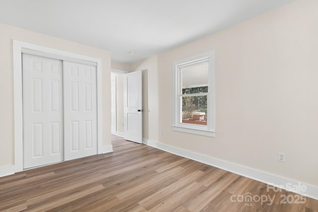 unfurnished bedroom featuring light wood-type flooring and a closet