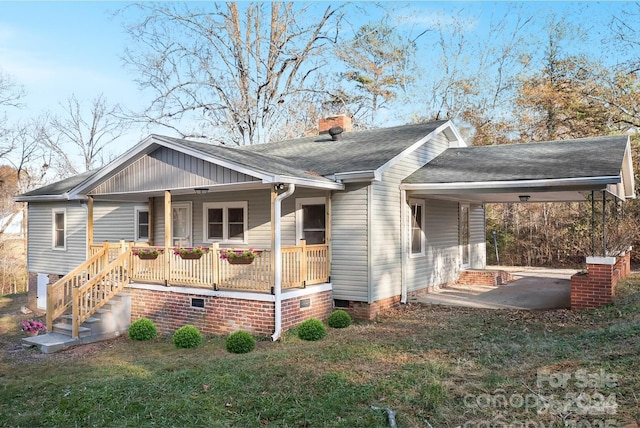 view of front facade featuring covered porch, a front yard, and a carport