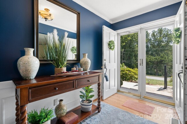 doorway to outside with crown molding, a healthy amount of sunlight, and light hardwood / wood-style flooring