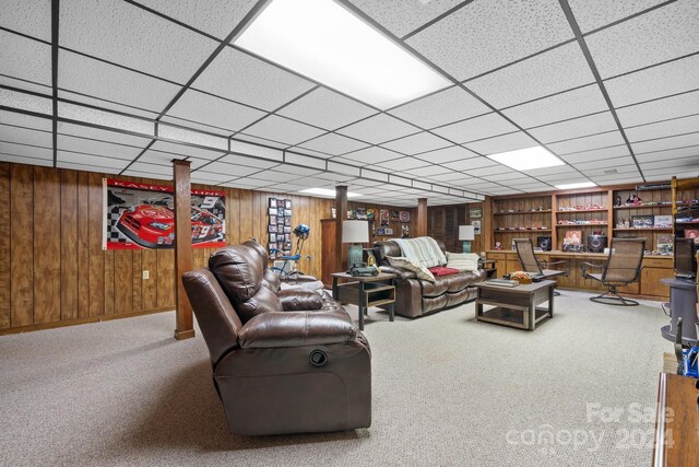 carpeted living room featuring a paneled ceiling and wooden walls