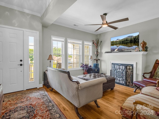 living room featuring hardwood / wood-style floors, ceiling fan, and crown molding