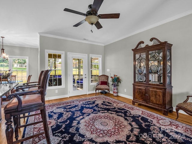 interior space with ceiling fan with notable chandelier, ornamental molding, and hardwood / wood-style floors