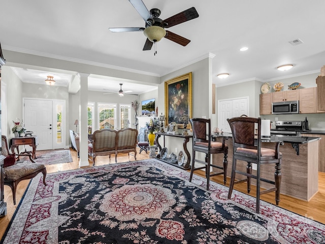 living room featuring ceiling fan, ornamental molding, and light wood-type flooring