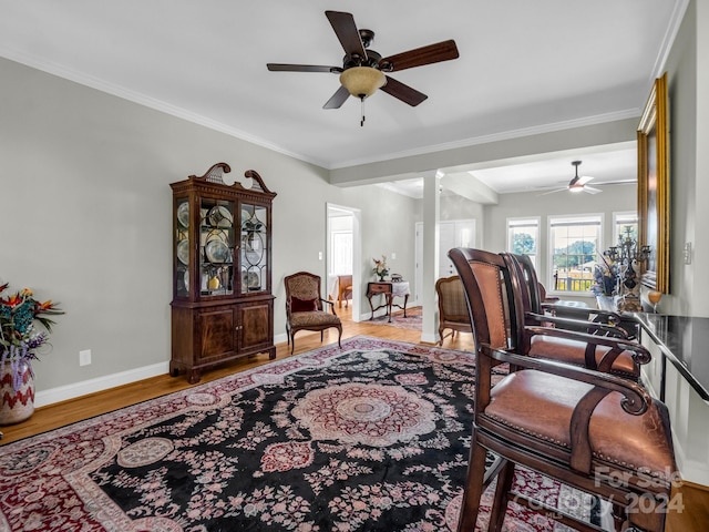 living room featuring crown molding, wood-type flooring, ornate columns, and ceiling fan